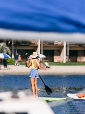A couple stand up paddling by the beach at the Catamaran Resort Hotel and Spa by Pacific Beach, San Diego, CA